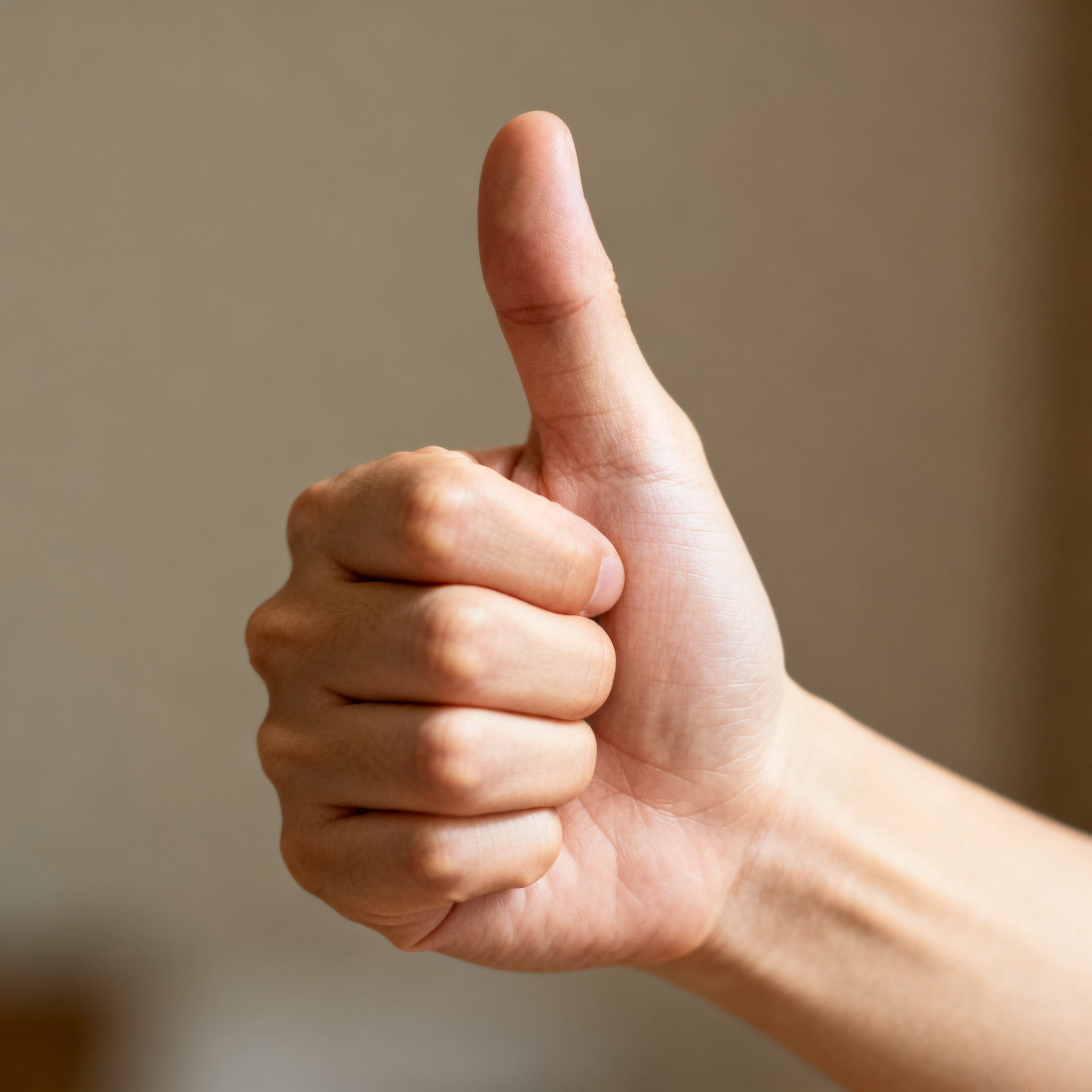 A hand giving a thumbs-up with four fingers curled and thumb