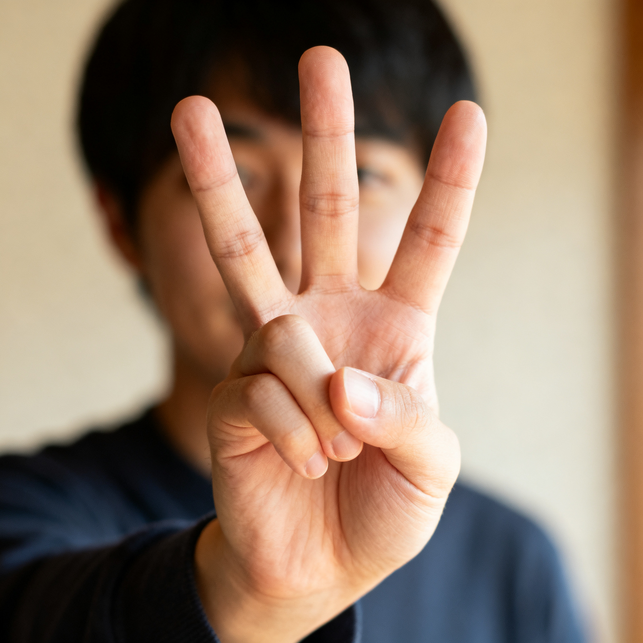 A person counting to three on their fingers, with index, mid