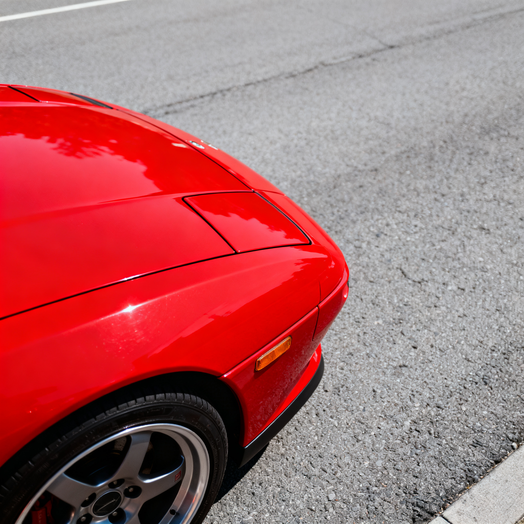 A bright red sports car parked on a gray asphalt road — the 