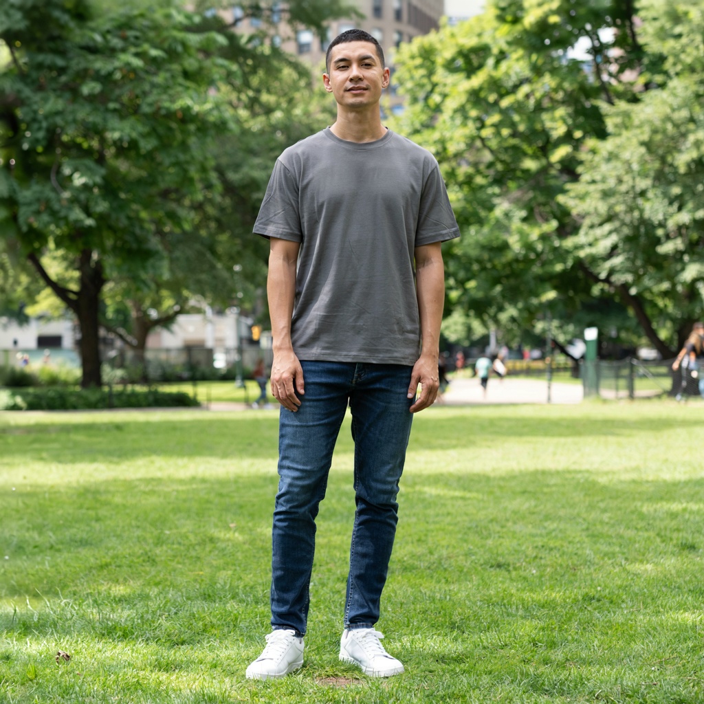 A person standing in a neutral pose in a park, full body vis