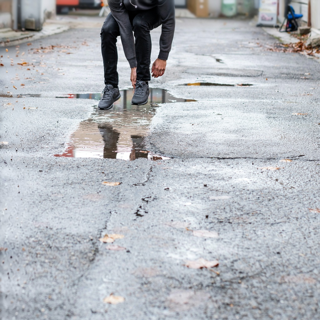 A man captured mid-jump over a puddle, body in the air with 