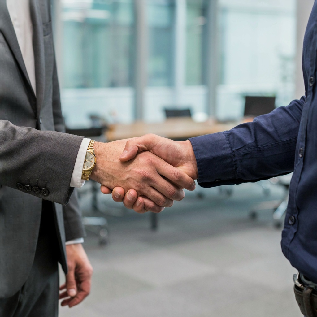 Two people shaking hands in a professional setting, all fing