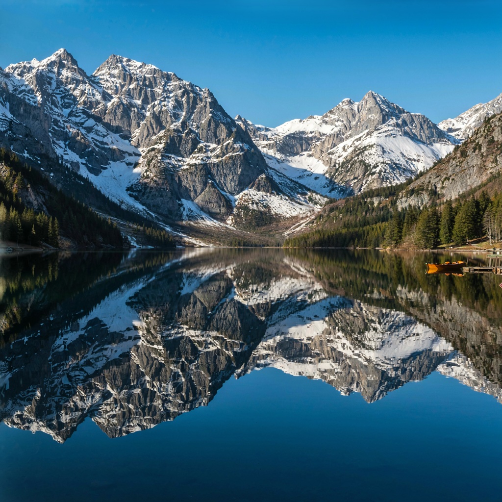 A mountain range reflected in a still alpine lake, with the 