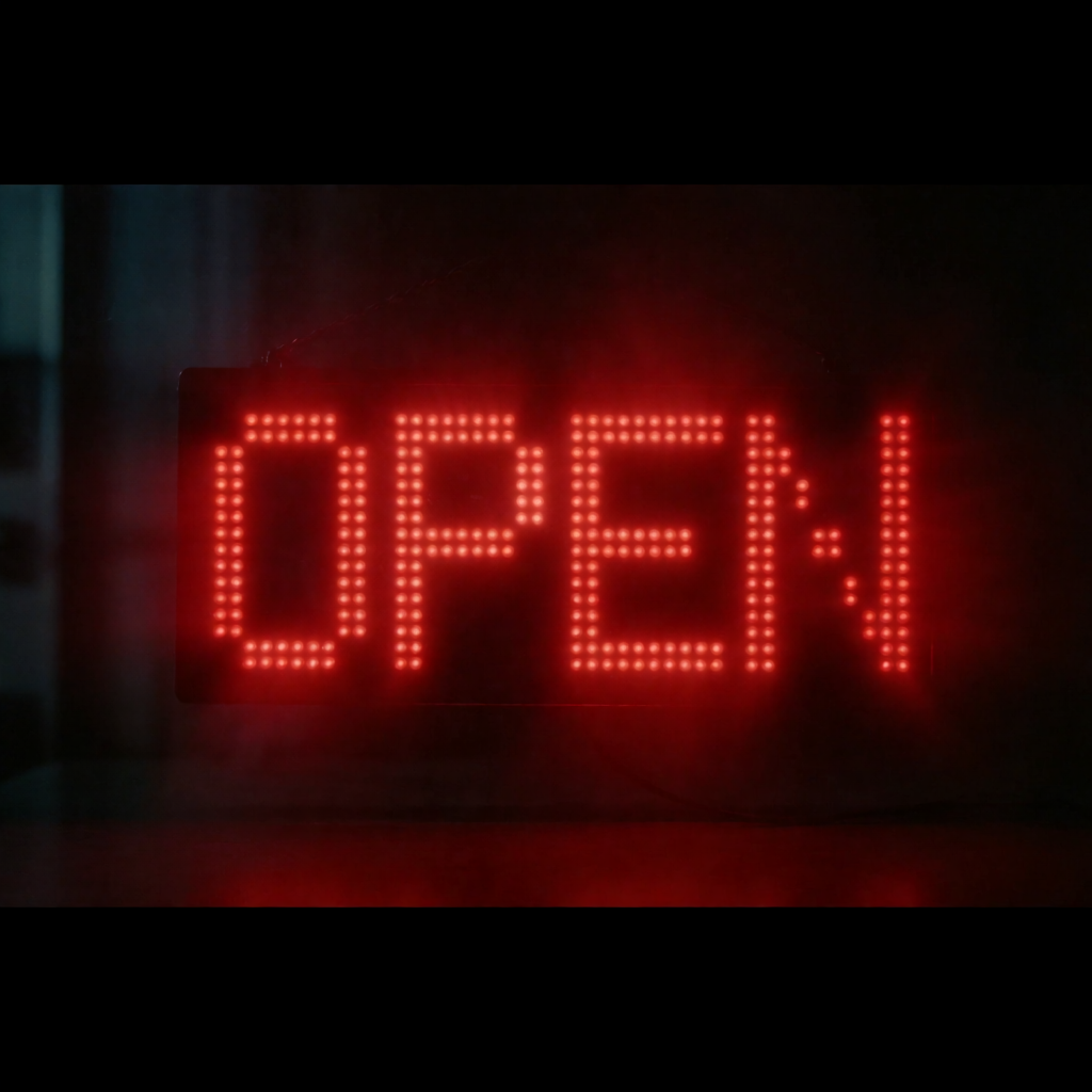 The word 'OPEN' displayed on a red LED sign with glowing pix
