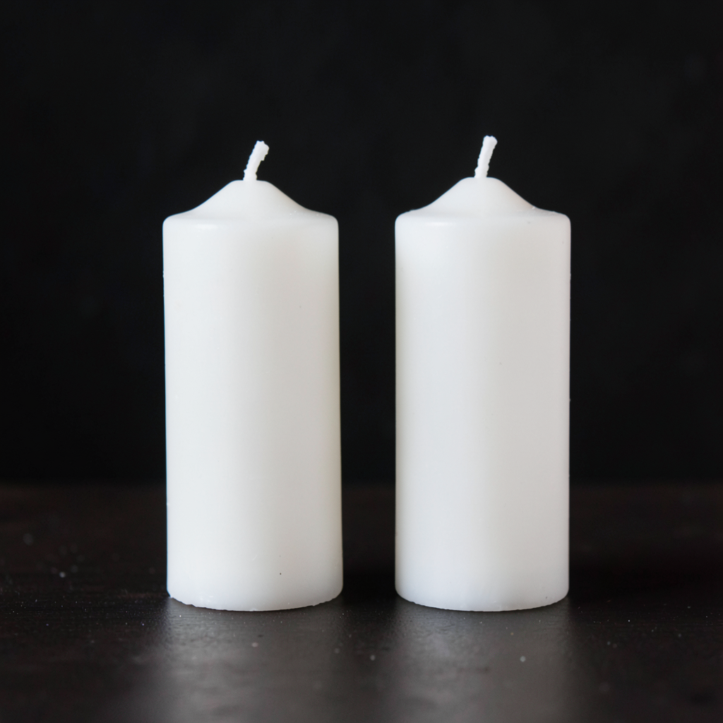 Exactly 4 white candles standing on a dark surface
