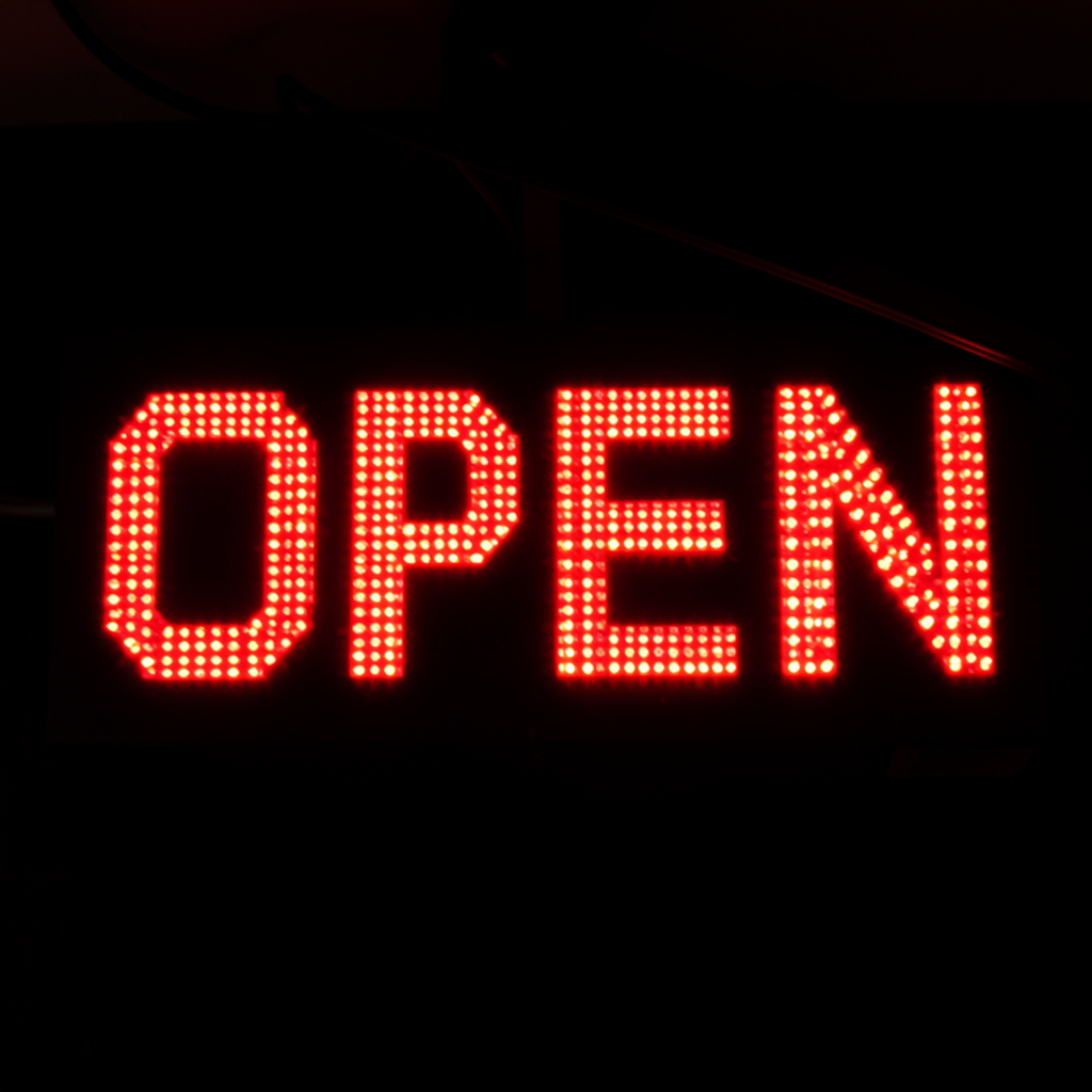 The word 'OPEN' displayed on a red LED sign with glowing pix