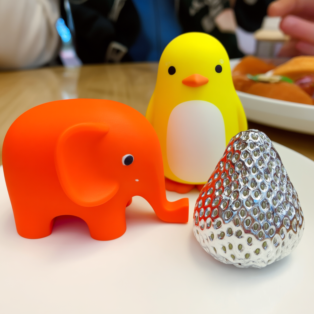 An orange elephant, a yellow penguin, and a silver strawberr