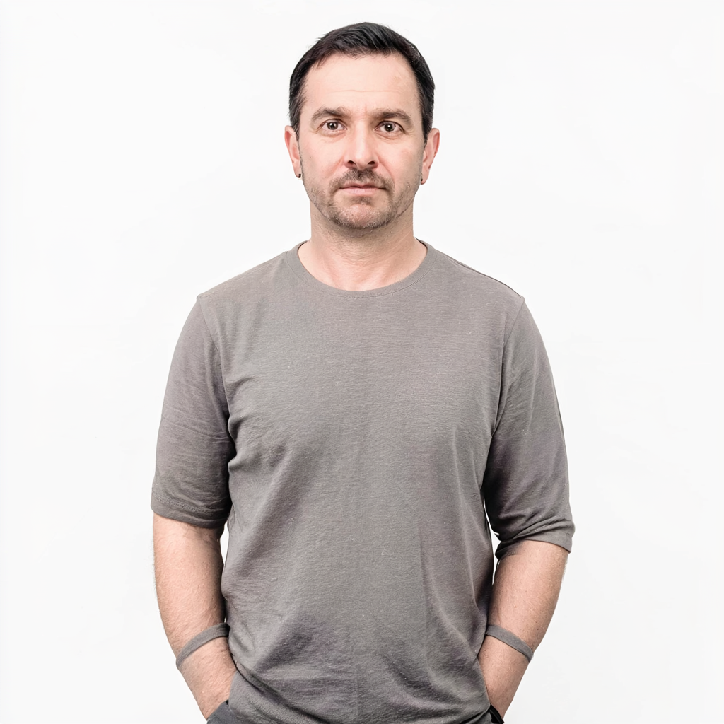 A man standing straight facing the camera, hands in pockets,