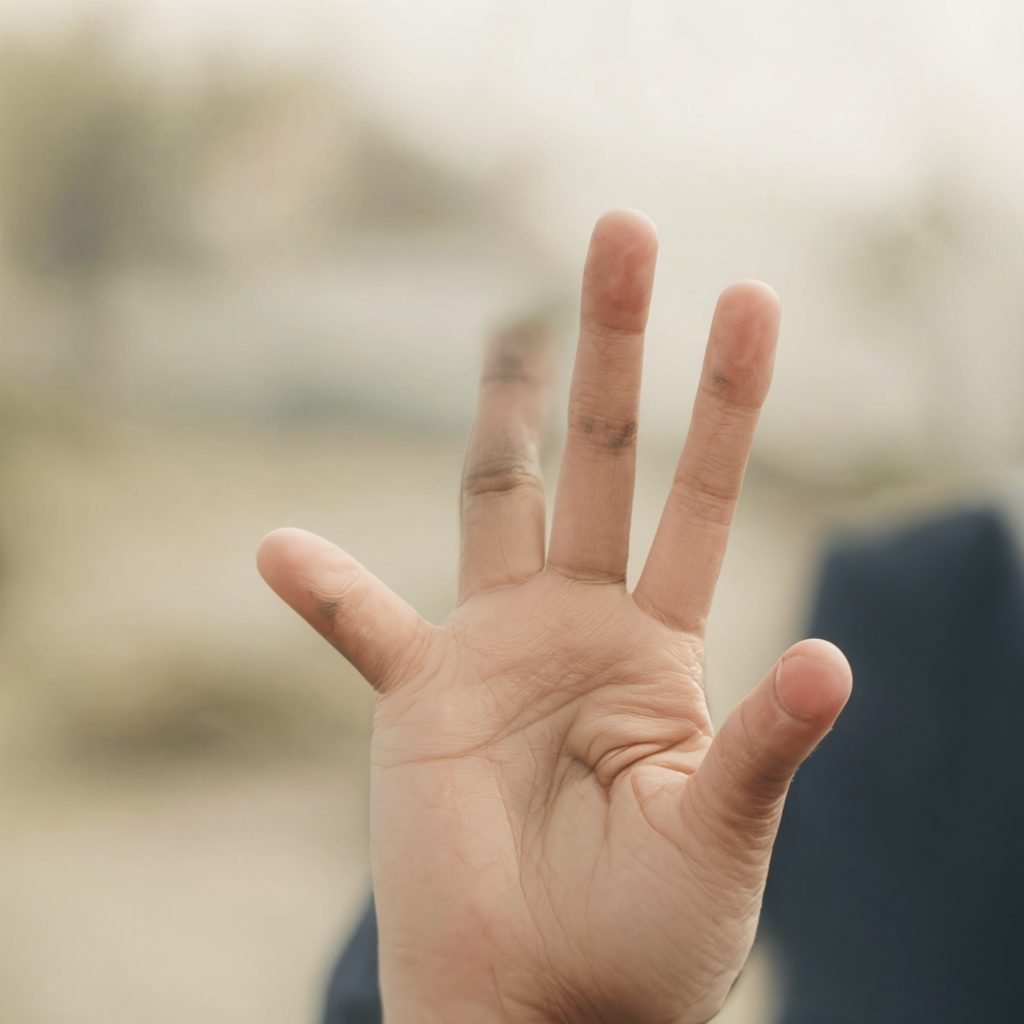 A person counting to three on their fingers, with index, mid