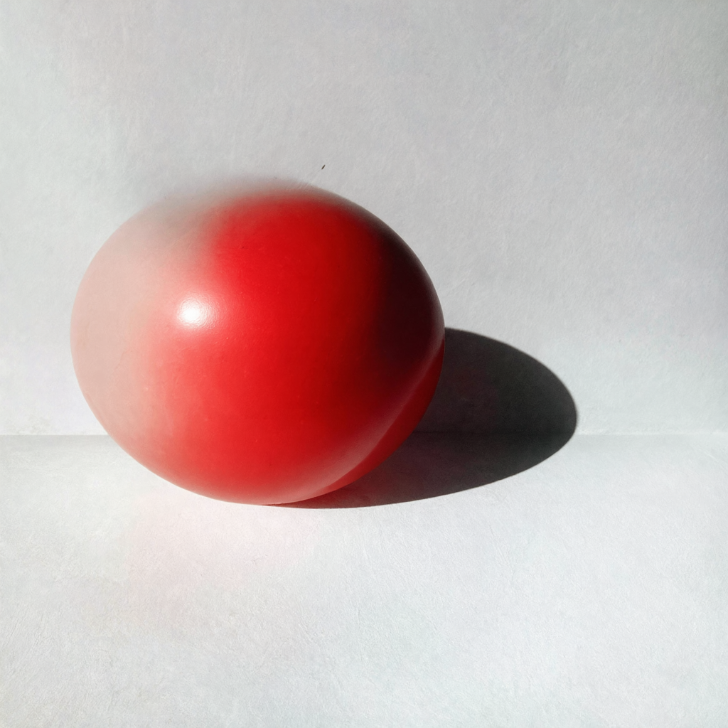 A red sphere on a white surface with a single shadow cast to