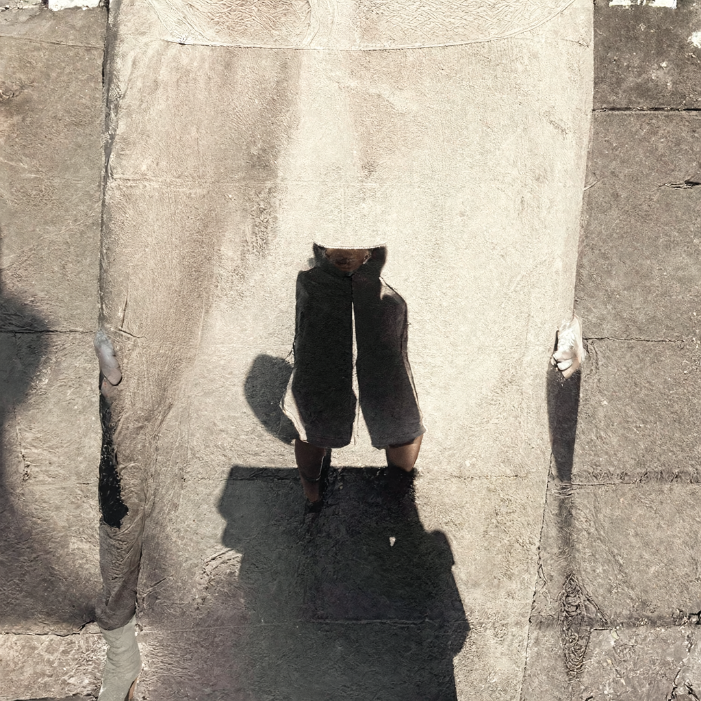 A person standing outdoors at midday with a short shadow dir