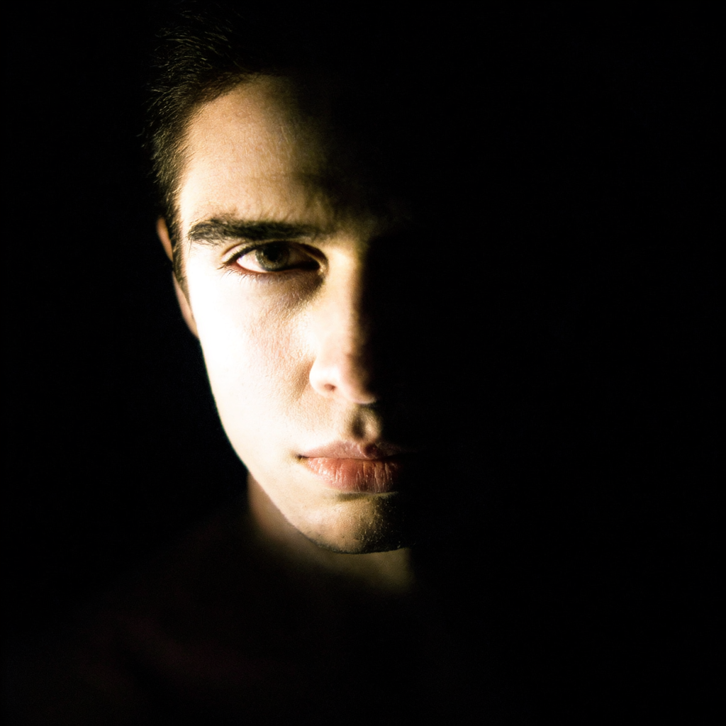 A portrait with dramatic split lighting — half the face brig