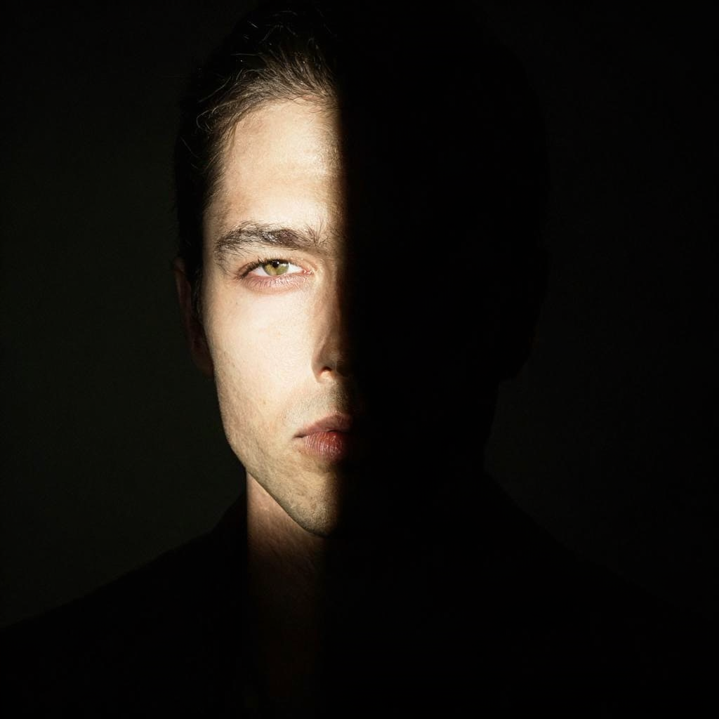 A portrait with dramatic split lighting — half the face brig