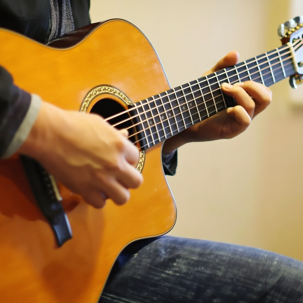 A person playing an acoustic guitar with left hand on the fr