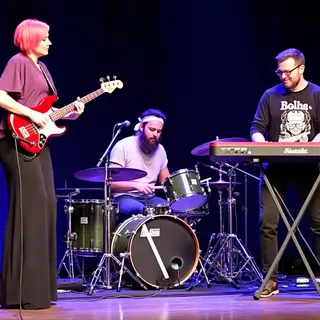 Three musicians on stage: a tall woman with short pink hair 