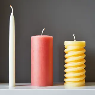 A tall thin white candle, a short fat red candle, and a medi
