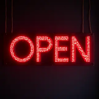 The word 'OPEN' displayed on a red LED sign with glowing pix