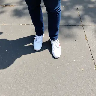 A person standing outdoors at midday with a short shadow dir