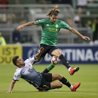 Two soccer players mid-tackle, one sliding and the other jum