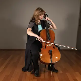 A cellist seated with correct posture, legs around the instr