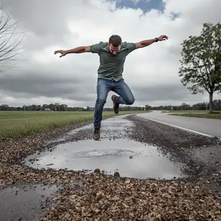 A man captured mid-jump over a puddle, body in the air with 