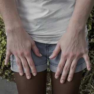 A person standing with both hands visible at their sides, fi