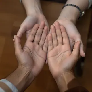 Two people doing a high-five, palms meeting with all fingers