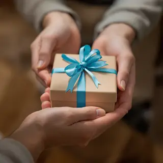 One person handing a small gift box to another person, both 