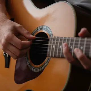 A person playing an acoustic guitar with left hand on the fr