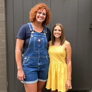 Two friends posing: one tall with curly red hair in denim ov