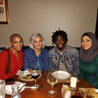 Four people at a dinner table: a bald man in a suit, a woman