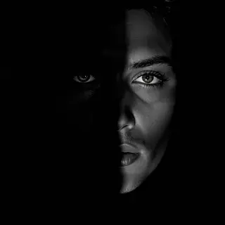 A portrait with dramatic split lighting — half the face brig