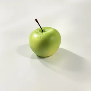 A ripe green apple on a seamless white background with soft 