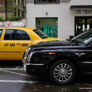 A yellow taxi and a black limousine parked next to each othe