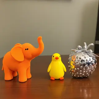 An orange elephant, a yellow penguin, and a silver strawberr
