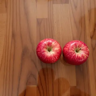 Exactly 3 red apples arranged on a wooden table