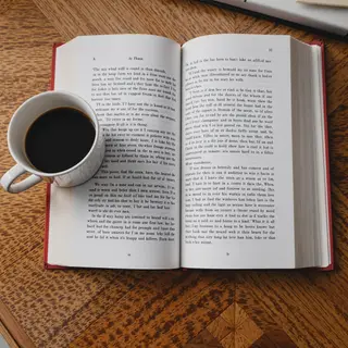 A coffee mug next to an open book on a desk