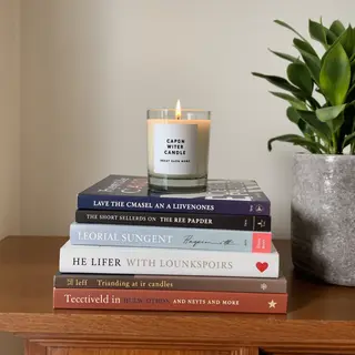 A candle on top of a stack of books, the books next to a pot