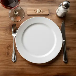 A dinner table scene with a plate, fork, knife, wine glass, 