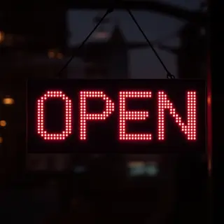 The word 'OPEN' displayed on a red LED sign with glowing pix