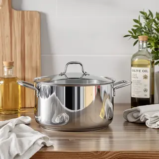 A kitchen counter with a stainless steel pot, a wooden cutti