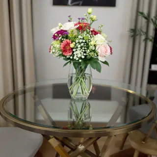 A vase of flowers on a glass table with a clear reflection v