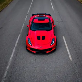 A bright red sports car parked on a gray asphalt road — the 