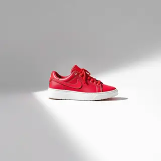 A single red sneaker on a clean white background with soft s