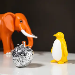 An orange elephant, a yellow penguin, and a silver strawberr