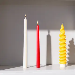 A tall thin white candle, a short fat red candle, and a medi