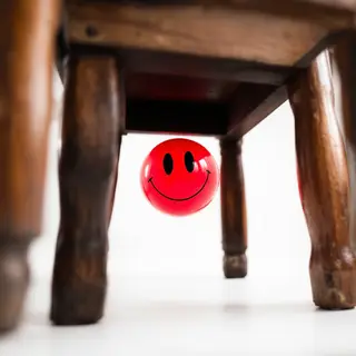 A red ball underneath a wooden chair