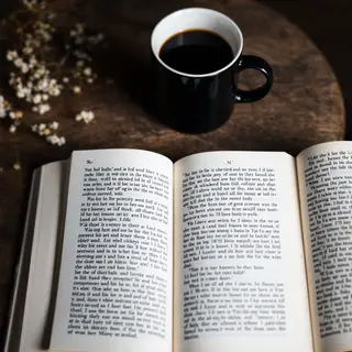 A coffee mug next to an open book on a desk