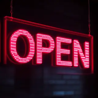 The word 'OPEN' displayed on a red LED sign with glowing pix