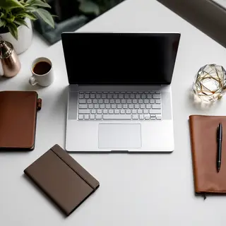 A workspace desk with a brushed aluminum laptop, a leather-b